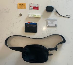 A Lululemon belt bag, wallet, and various items arranges on a table.
