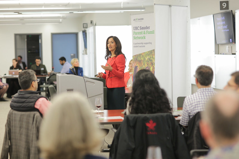 A woman at a podium talking to a group of people who are seated