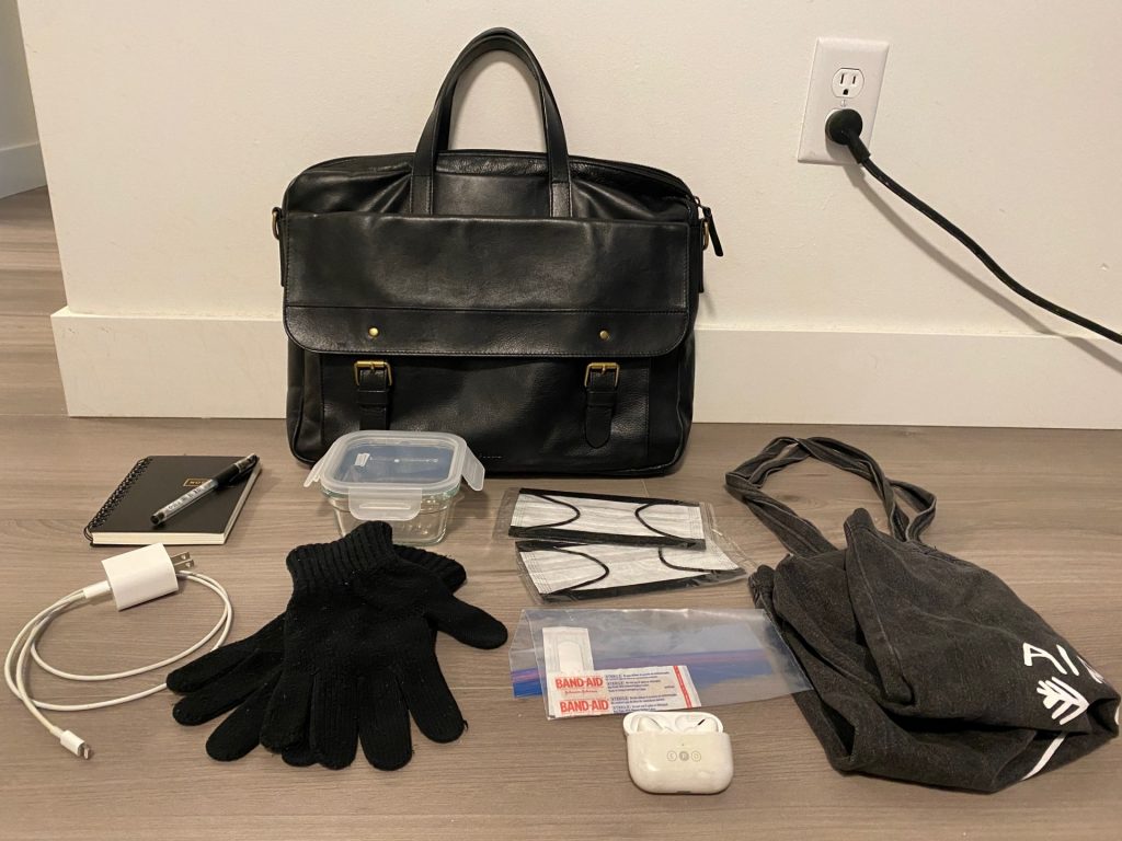 A black handbag along with its contents, arranged on a floor.