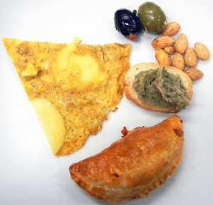 a plate of tapas including the cheese and olive empanada