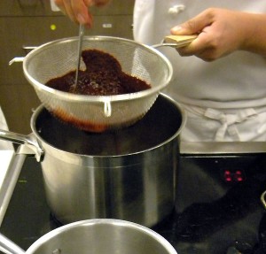 straining the blended chiles into hot oil