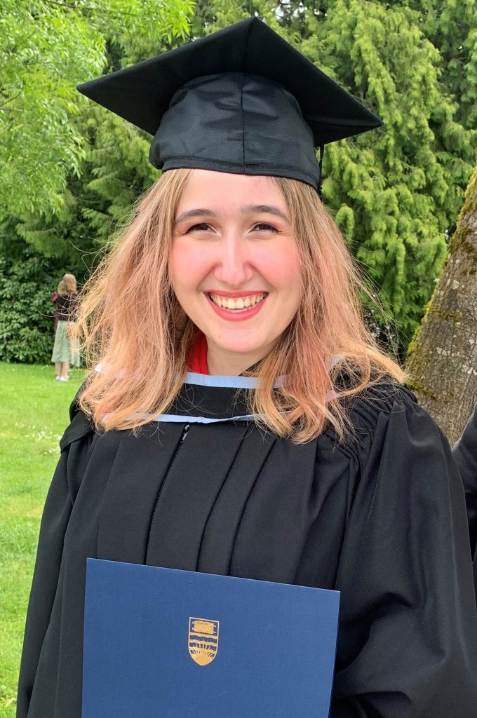 Maya in graduation robe and hat with diploma