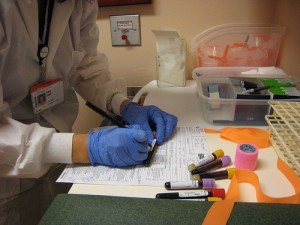Image shows a lab technician analyzing a blood sample. Image courtesy of nita lind