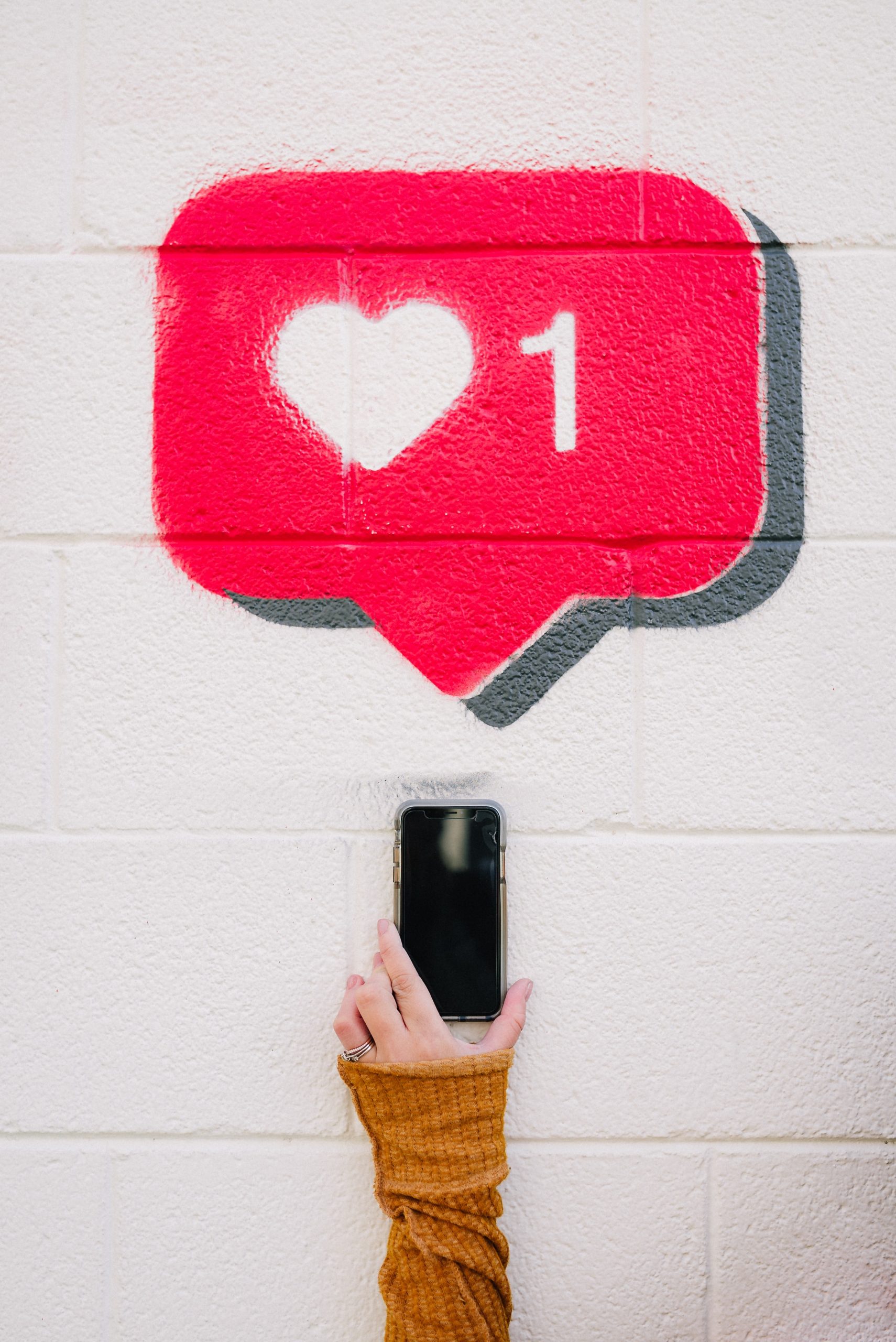 A hand holding a phone with an Instagram like logo