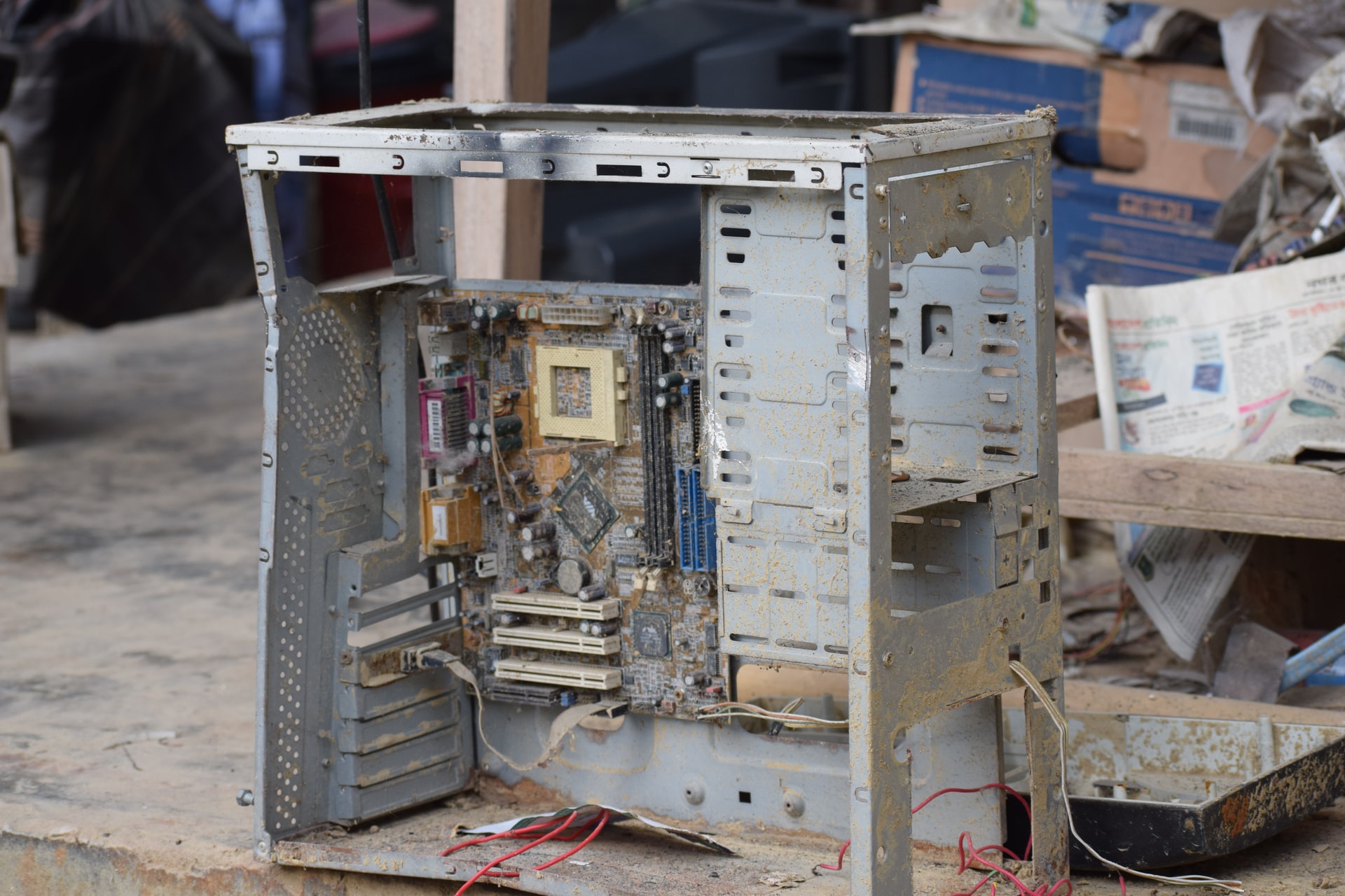 A square, gray, damaged electronic device with no cover on it.