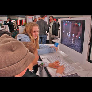 Kids on PC teaching adults at a conference how to play a game