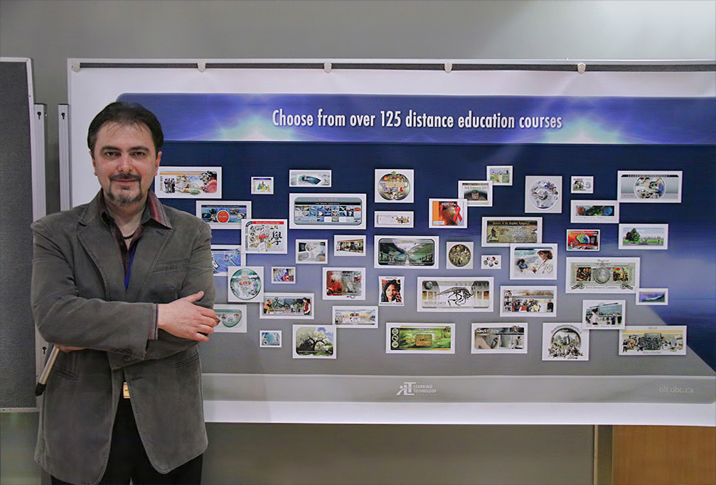 Gabriel Lascu posing with one of his poster creations, which is a collage of some of his older graphic desigs /illustrations.