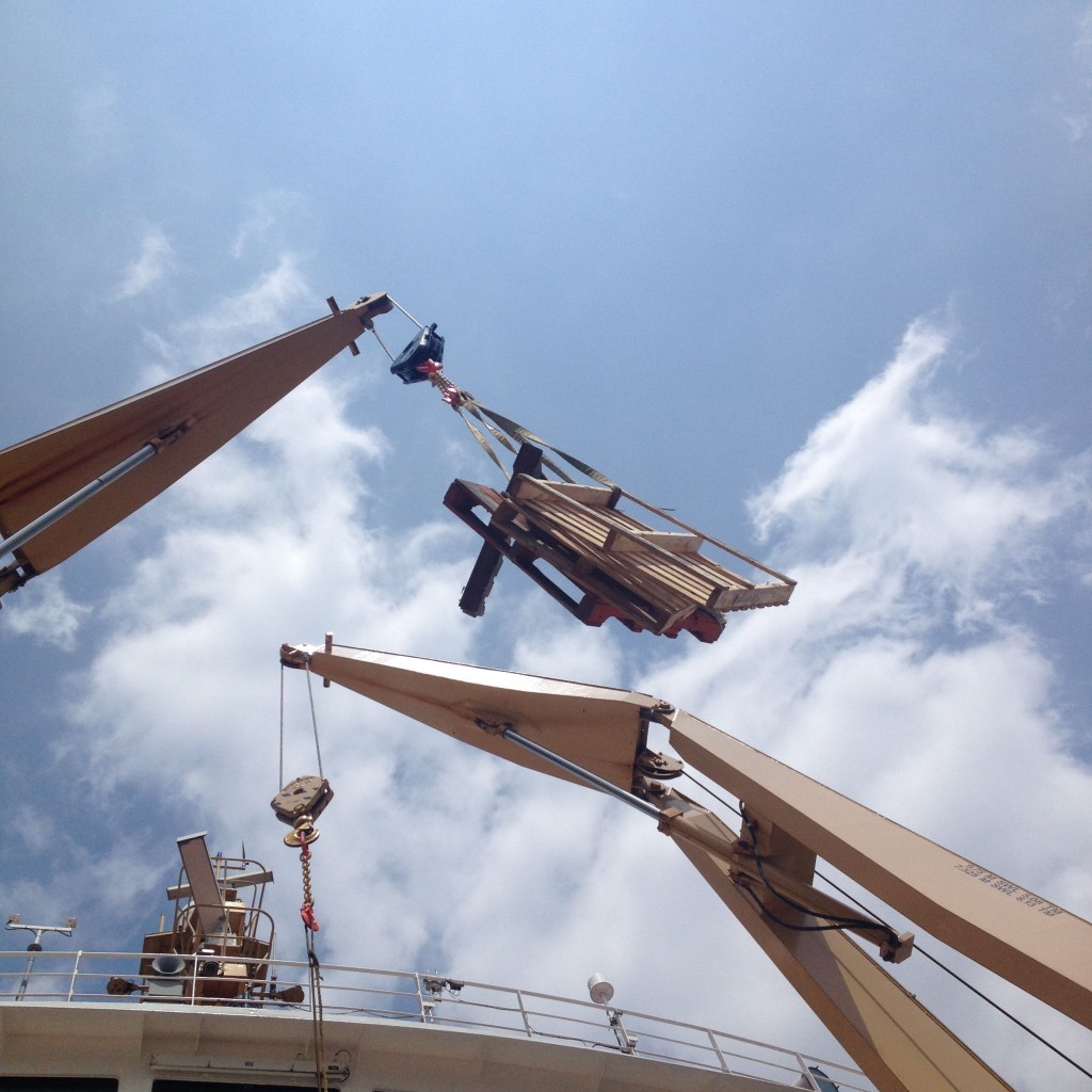 Cranes lifting pallets back off the ship.