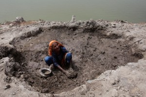 A 90 year old woman gathers mud to build a house