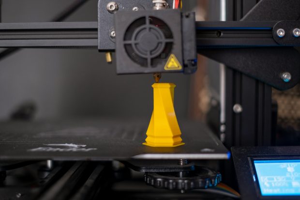 An FDM 3D printer applying a new layer to the cone shaped part on the printing bed.