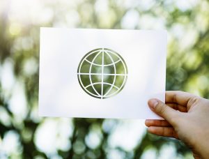 Hand showing perforated globe shape paper on green nature background