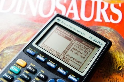 a ti-83 calculator laying on a dino magazine