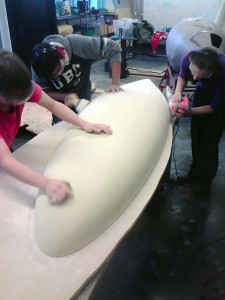 Team members sanding the plug for the most recent hull.